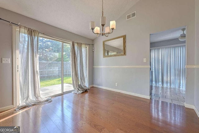 spare room featuring wood-type flooring, lofted ceiling, and a wealth of natural light