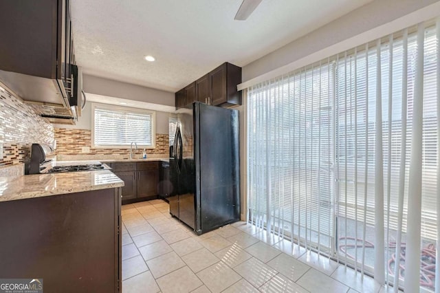 kitchen featuring appliances with stainless steel finishes, light stone countertops, light tile patterned floors, and backsplash