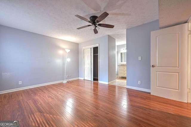 unfurnished bedroom with ceiling fan, a textured ceiling, hardwood / wood-style flooring, a closet, and ensuite bathroom