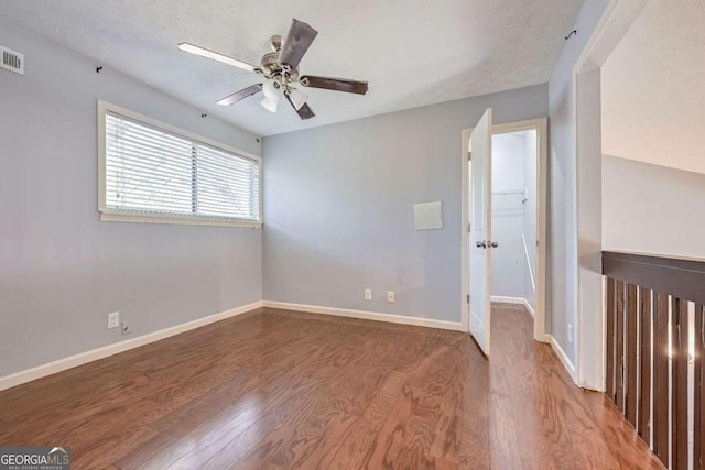 empty room featuring ceiling fan, hardwood / wood-style flooring, and a textured ceiling