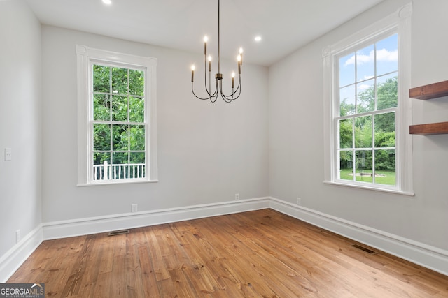 spare room featuring a notable chandelier and light hardwood / wood-style floors