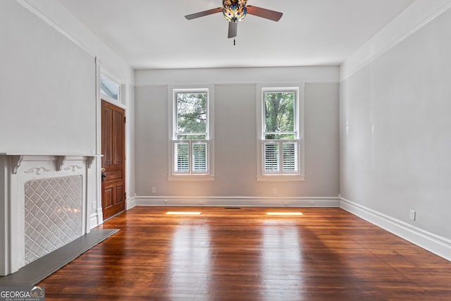 unfurnished living room with crown molding, ceiling fan, and dark wood-type flooring