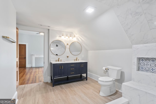 bathroom featuring ceiling fan, toilet, lofted ceiling, hardwood / wood-style flooring, and vanity