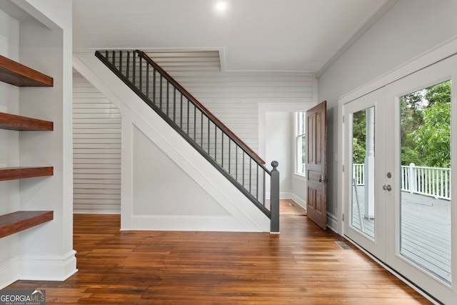 entryway with ornamental molding, wooden walls, dark wood-type flooring, and french doors