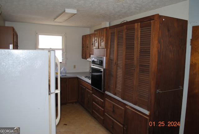 kitchen with oven, a textured ceiling, and white fridge