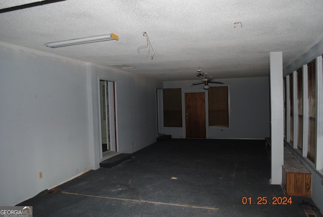 empty room with ceiling fan and a textured ceiling