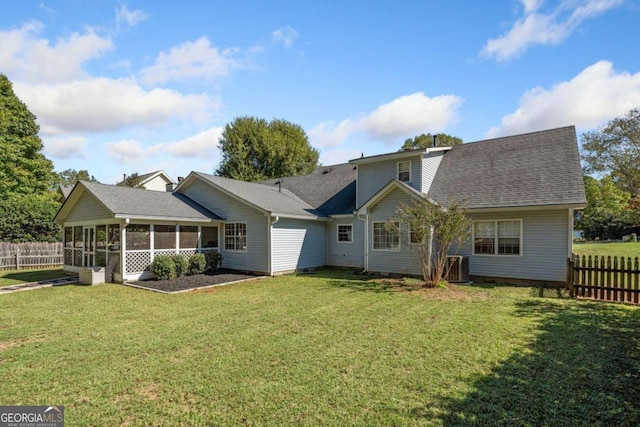 rear view of property featuring a yard and a sunroom