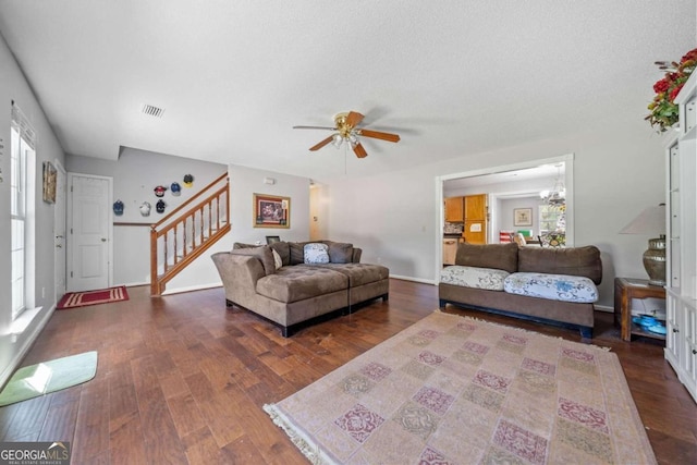 living room featuring ceiling fan with notable chandelier, a textured ceiling, and dark hardwood / wood-style flooring