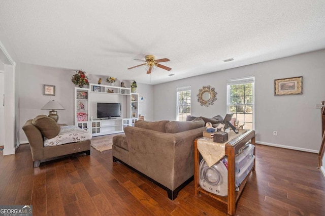 living room featuring ceiling fan, a textured ceiling, and dark wood-type flooring