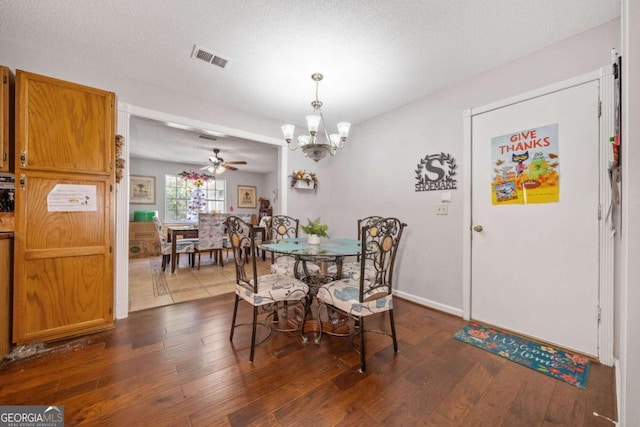 dining space featuring ceiling fan with notable chandelier, dark hardwood / wood-style floors, and a textured ceiling