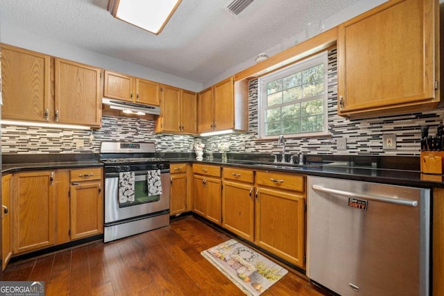 kitchen featuring backsplash, sink, dark hardwood / wood-style flooring, appliances with stainless steel finishes, and a textured ceiling