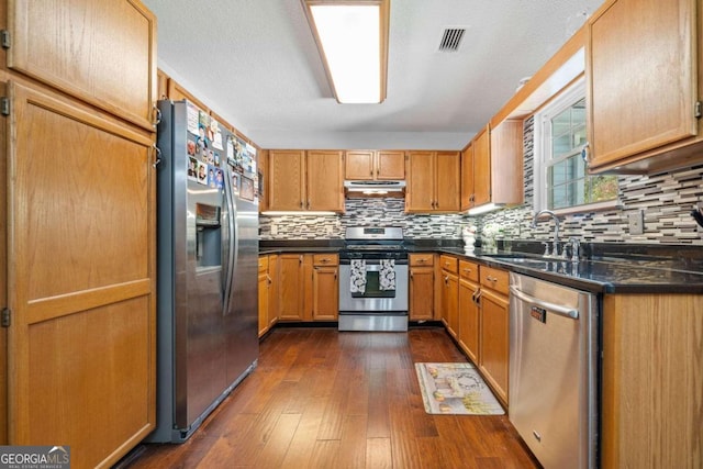 kitchen with a textured ceiling, sink, dark hardwood / wood-style flooring, appliances with stainless steel finishes, and backsplash