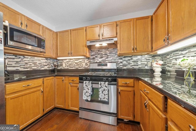 kitchen with a textured ceiling, appliances with stainless steel finishes, dark hardwood / wood-style floors, and tasteful backsplash