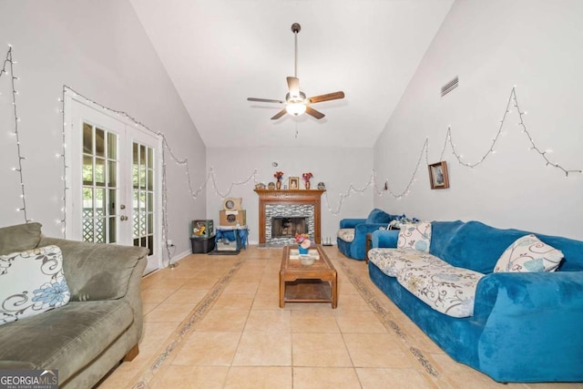 living room with high vaulted ceiling, ceiling fan, french doors, a tiled fireplace, and light tile patterned floors