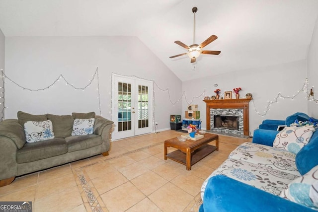 living room featuring ceiling fan, light tile patterned floors, french doors, a tiled fireplace, and vaulted ceiling