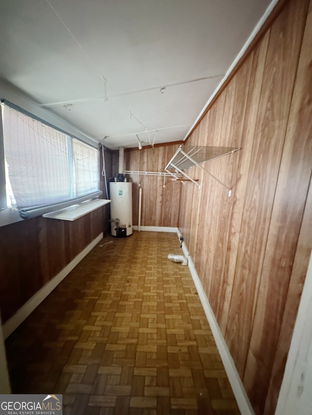 hall featuring wooden walls, water heater, and dark parquet flooring