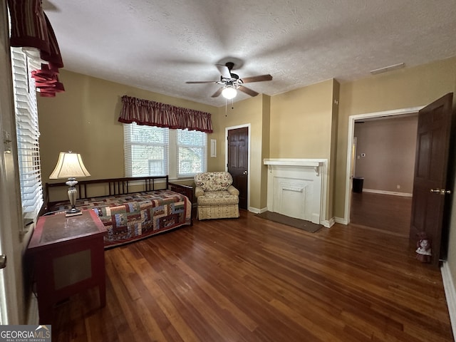 living room featuring dark hardwood / wood-style floors, a textured ceiling, a fireplace, and ceiling fan