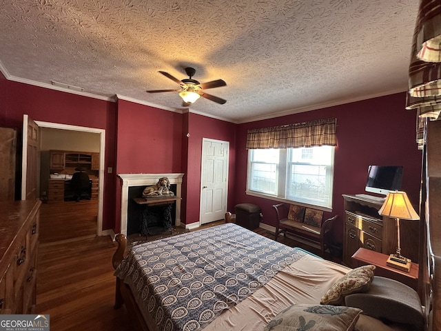 bedroom with a closet, dark wood-type flooring, ornamental molding, a textured ceiling, and ceiling fan