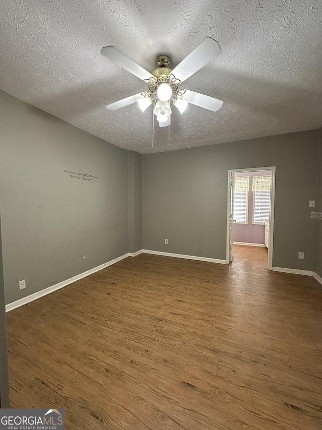 empty room with ceiling fan, hardwood / wood-style flooring, and a textured ceiling