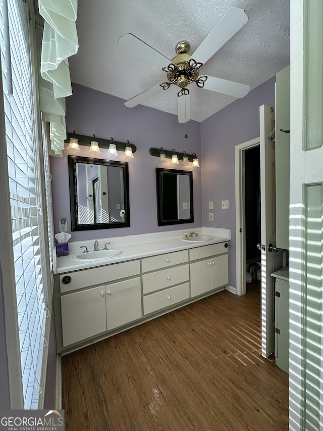 bathroom featuring vanity, ceiling fan, hardwood / wood-style flooring, and a textured ceiling