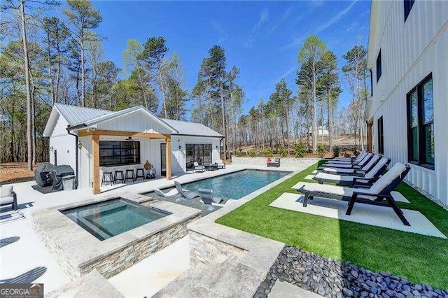 view of swimming pool with an outbuilding, a patio, and an in ground hot tub