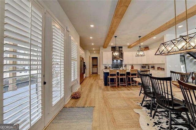 dining space with light hardwood / wood-style flooring and beamed ceiling