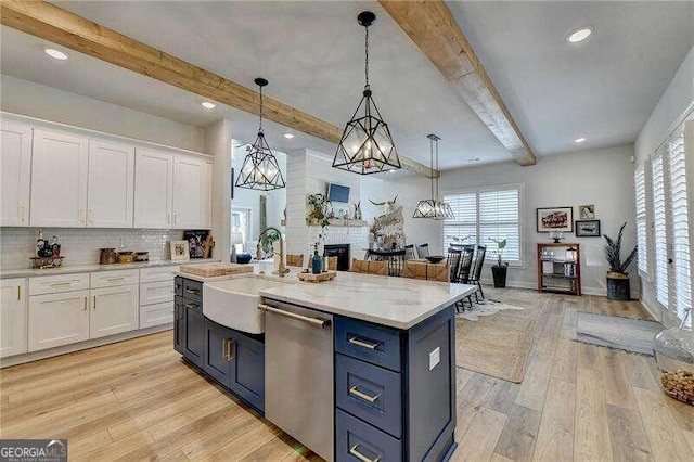 kitchen featuring dishwasher, white cabinetry, hanging light fixtures, and a kitchen island with sink