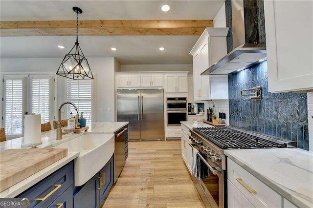 kitchen with white cabinetry, wall chimney exhaust hood, and premium appliances