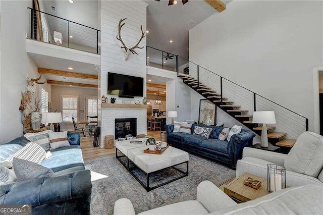 living room featuring ceiling fan, a fireplace, a high ceiling, and hardwood / wood-style flooring