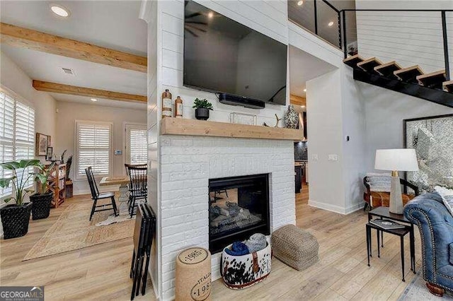 living room with beam ceiling, a fireplace, wood-type flooring, and plenty of natural light