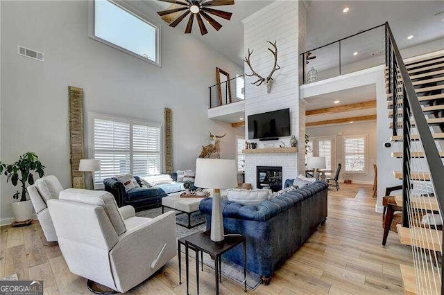 living room featuring light hardwood / wood-style floors, a brick fireplace, ceiling fan, and plenty of natural light