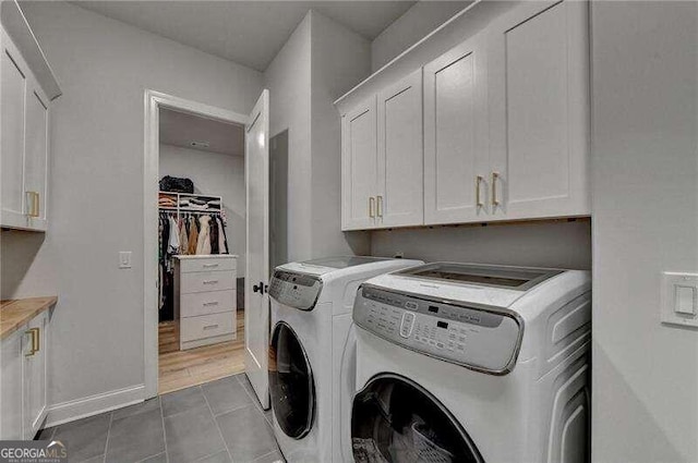 washroom with cabinets, washing machine and dryer, and tile patterned flooring