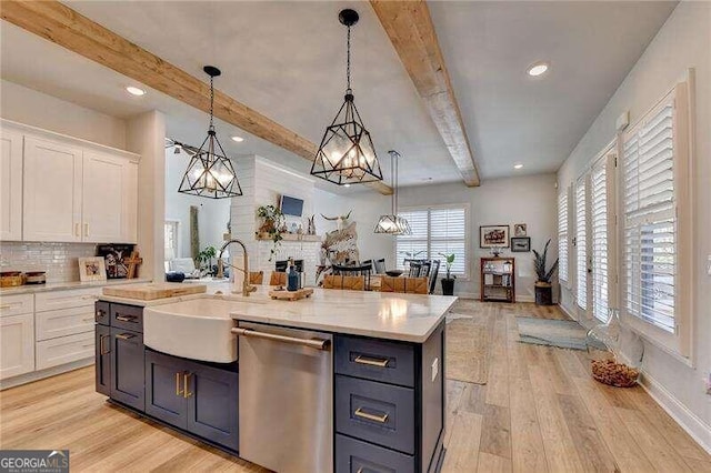 kitchen with sink, hanging light fixtures, light hardwood / wood-style flooring, stainless steel dishwasher, and white cabinetry