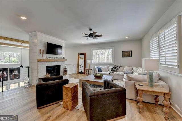 living room featuring a wealth of natural light, ceiling fan, a fireplace, and light hardwood / wood-style floors