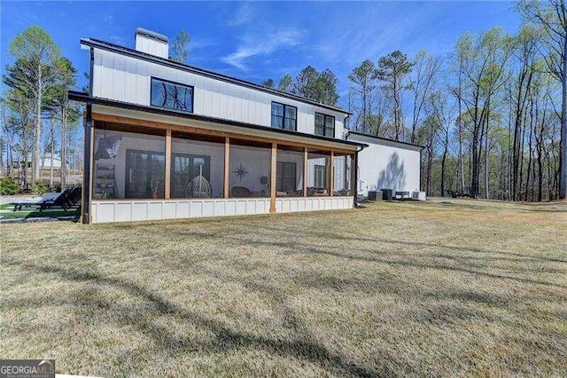 back of house featuring a lawn and a sunroom