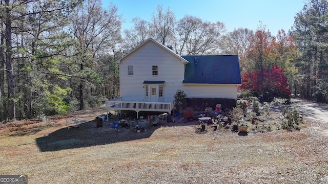 rear view of house with a lawn and a wooden deck