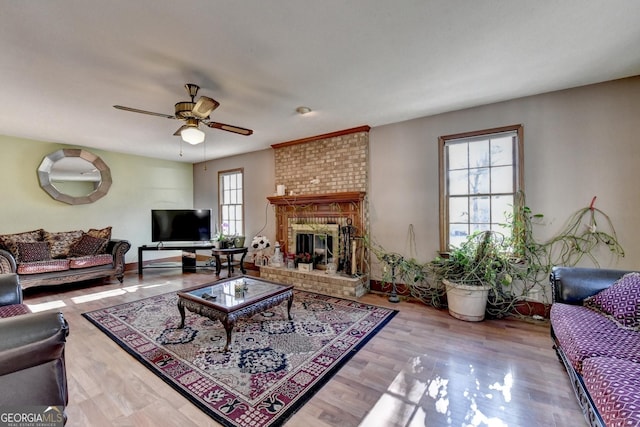 living room with a fireplace, ceiling fan, hardwood / wood-style floors, and a healthy amount of sunlight