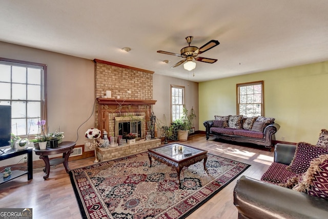 living room featuring a brick fireplace, light hardwood / wood-style flooring, and a healthy amount of sunlight