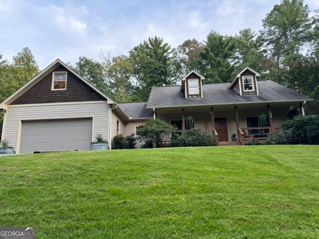 view of front of property featuring a garage, a porch, and a front lawn