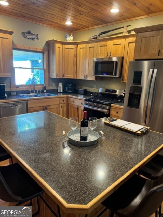 kitchen with appliances with stainless steel finishes, a center island, sink, and a breakfast bar