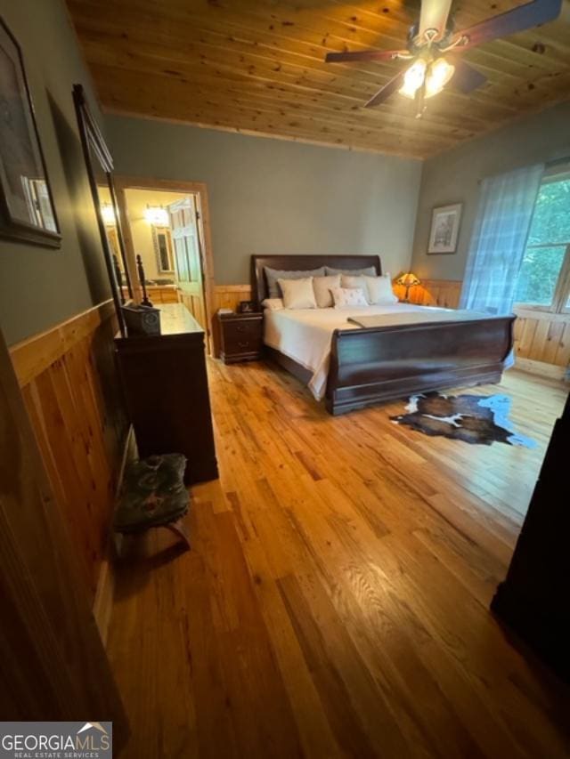 bedroom featuring ceiling fan, wooden walls, wood ceiling, and light hardwood / wood-style floors