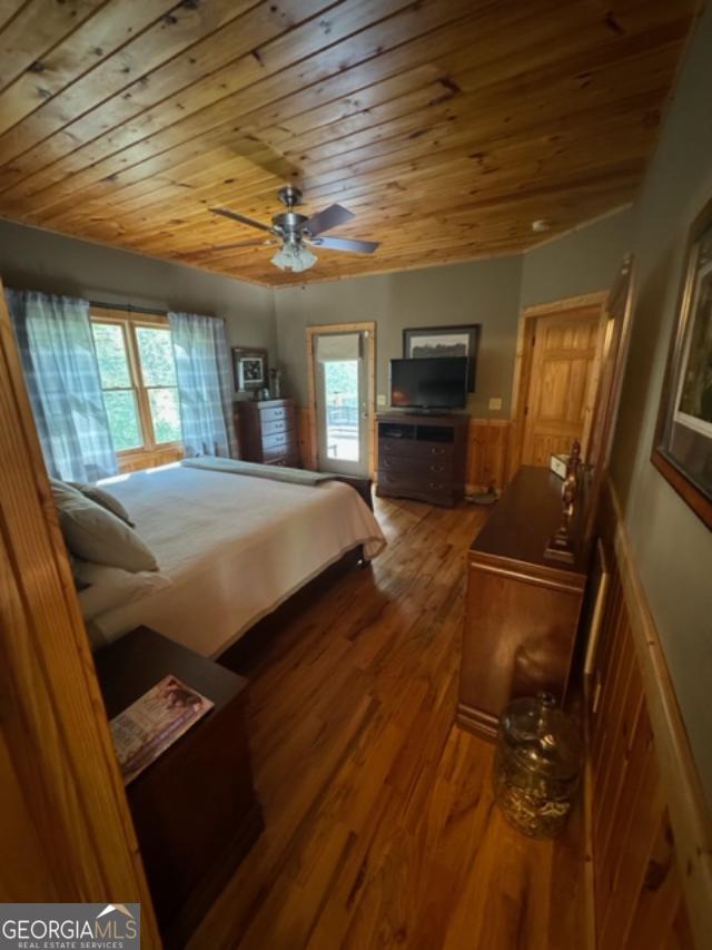 bedroom featuring ceiling fan, hardwood / wood-style flooring, wood ceiling, and wood walls