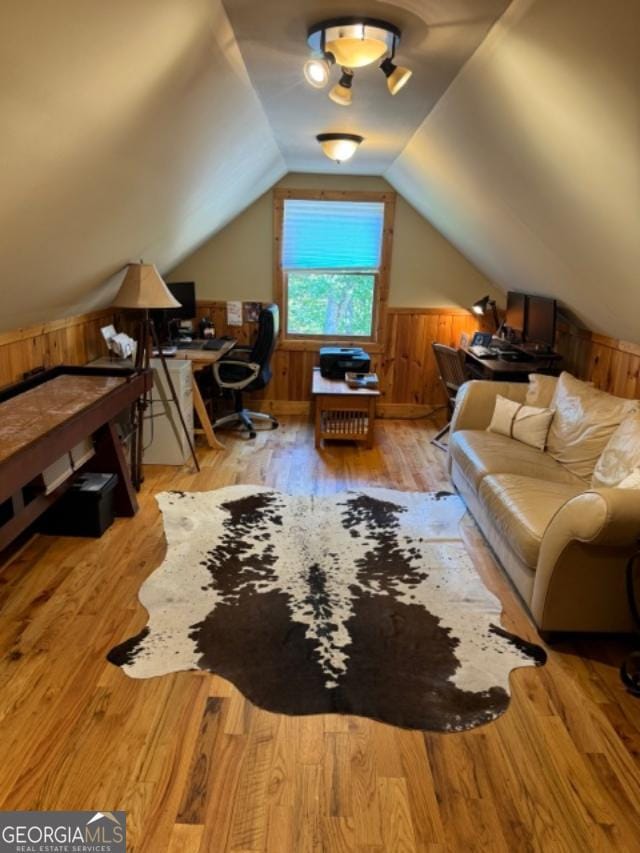 interior space with wooden walls, light wood-type flooring, and lofted ceiling