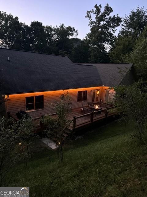 back house at dusk with a yard and a wooden deck