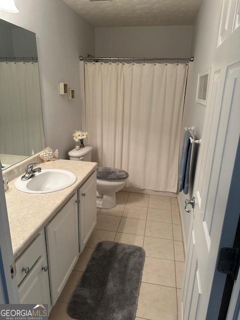 bathroom with a textured ceiling, tile patterned floors, vanity, and toilet