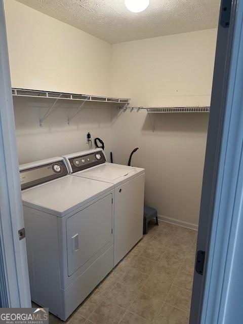 washroom with a textured ceiling and washer and clothes dryer