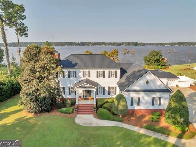 colonial inspired home featuring a front yard, a porch, and a water view