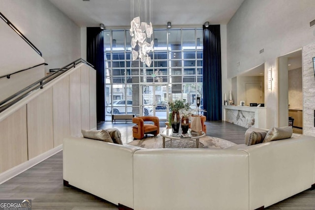 living room with a chandelier, a high ceiling, dark hardwood / wood-style flooring, and a wall of windows