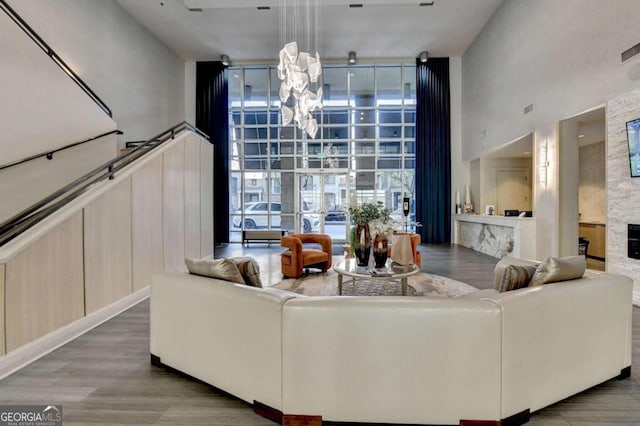 living room featuring a high ceiling, a wall of windows, a fireplace, and hardwood / wood-style flooring