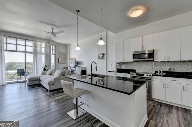 kitchen featuring white cabinets, an island with sink, appliances with stainless steel finishes, and sink